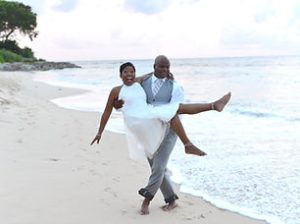 Groom lifting bride at beach wedding in Barbados